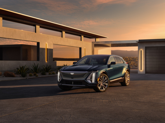 A sleek, modern SUV with angular design sits in front of a contemporary building at sunset. Warm lighting and clean lines create a luxurious ambiance.