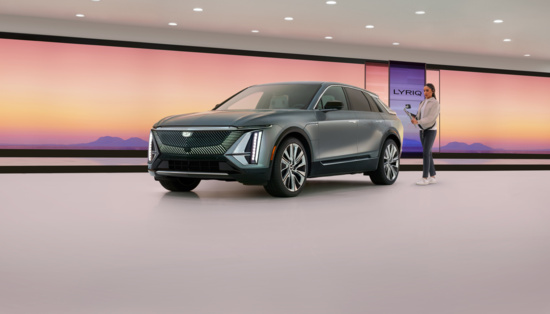 A sleek, modern SUV is showcased in a minimalist room with a large digital screen displaying a serene sunset. A person interacts with the display, adding a futuristic touch.