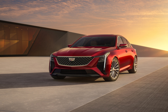 A sleek red cadillac ct5 is parked on a modern concrete driveway at sunset. The car's sharp angles and bold grille create a sense of elegance and power.