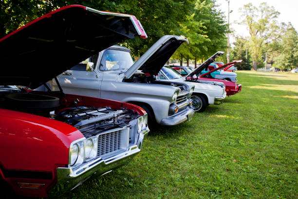 Raised hoods showcase engines of vintage cars at summer car show. USA 1970's vehicles.