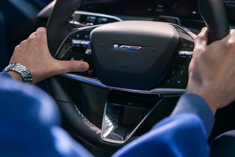 Close-up of a Man About to Press the V-Button on the 2026 OPTIQ-V Steering Wheel | Turan Foley Cadillac in Gulfport MS