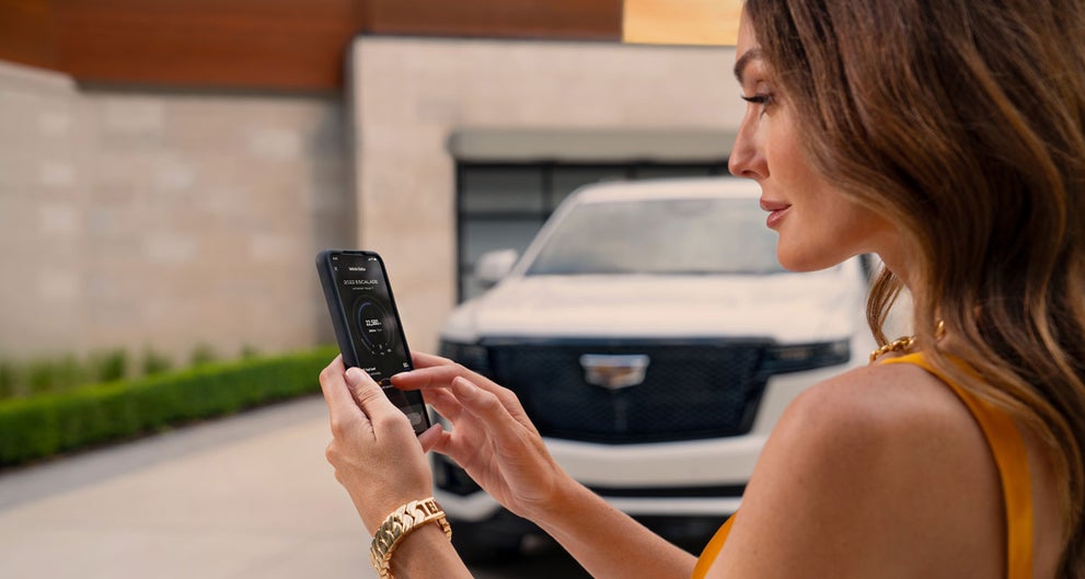 lady checking her mobile with a Cadillac vehicle background | Turan Foley Cadillac in Gulfport MS